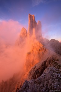 <p>Brilliant sunset light illuminates the Vajolet Towers in the Rosengarten as misty clouds swirl off the peaks.</p>